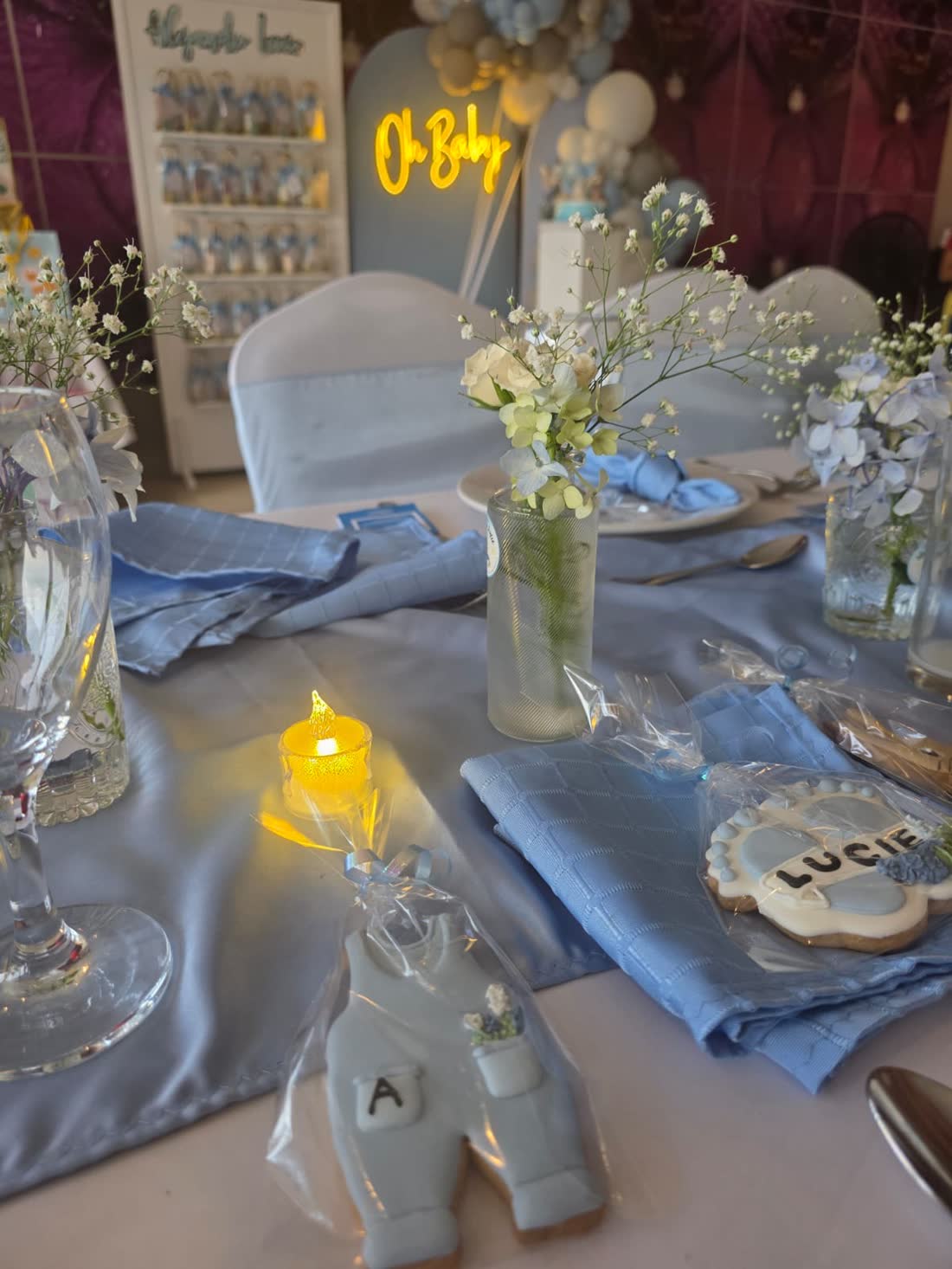 Mesa azul con vajilla clara, detalles botánicos y una vela cálida en montaje ETERIA.