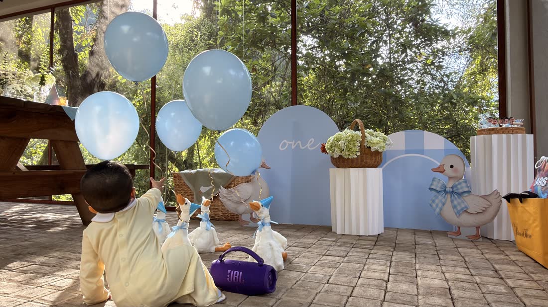 Montaje exterior ETERIA con globos azul cielo, cilindros decorativos y flores blancas.